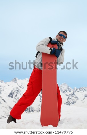 Pretty man with red snowboard in red pants