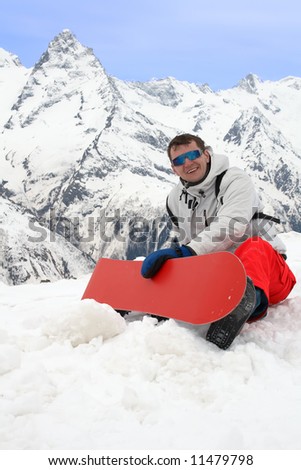 Happy man with red snowboard in mountains