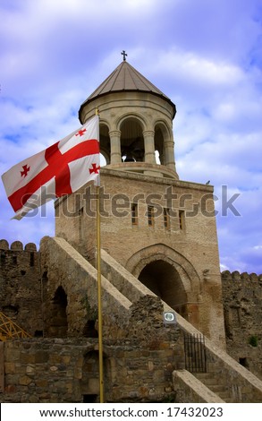 Georgian national red flag over orthodox church and blue sky