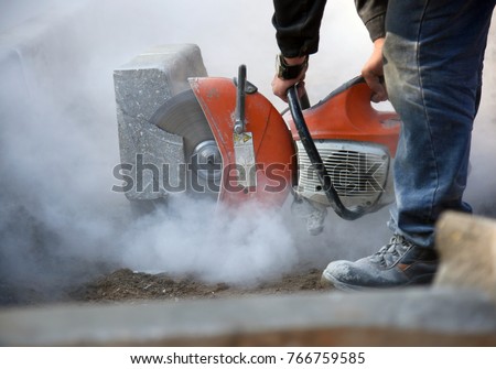 A worker cuts concrete curb circular saw at a construction site