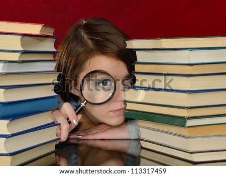Girl looking at camera through magnifier. On a red background.
