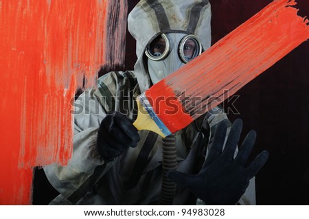 The person in a gas mask paints over glass a red paint