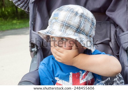 scared little boy covers mouth with her hand