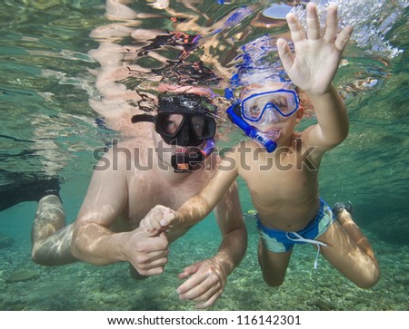 Little son hand hold father hand. Underwater image.