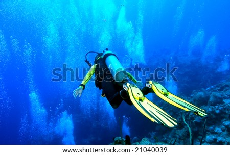 A diver is in \'free fall\' position, gliding over the edge of an abyss that drops to 6000 ft! Shot on the wall of Grand Cayman against a backdrop of copious bubbles from divers below.