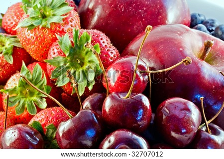 A selection of red summer fruit: strawberries, cherries and apples.