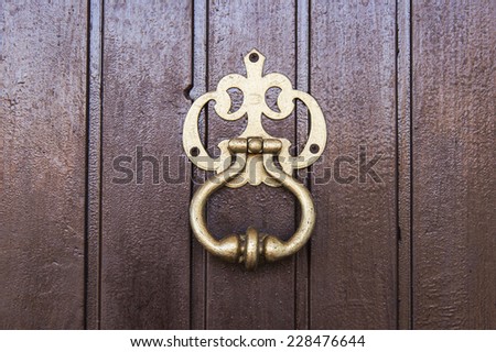 Old door knocker on dark wooden door close up