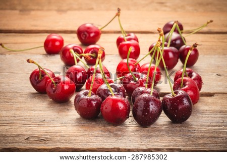 Cherries on wooden rural table with water drops macro background