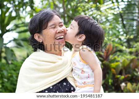 Young grandson giving his grandma a big smooch on the cheek,Asian people