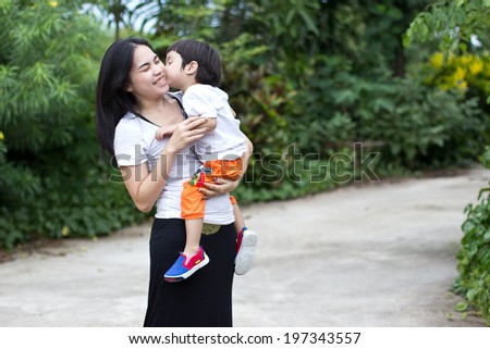 the boy giving his mother a big smooch on the cheek,Asian people,thailand people