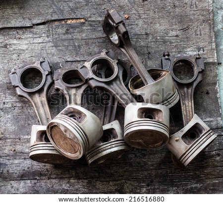 Worn out piston and connecting rod, dismantled from the internal combustion engine on wood background