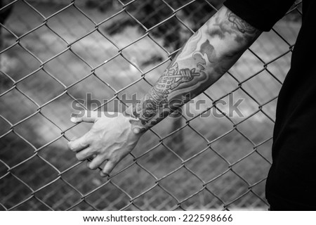 hand in jail, tattoo on hand,hand clutching prison,no escape,monochrome