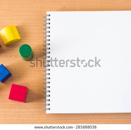 White blank page sketch book and colorful building blocks on wood table