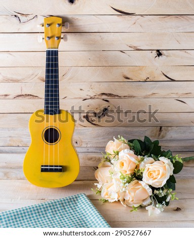 ukulele guitar with rose on wood background