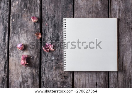 note book paper and onions on old wooden background