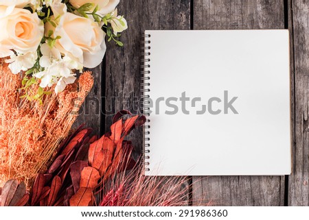 note book with rose ,hay and dry leaves on old wood background