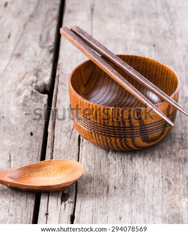 Wooden bowls, wooden spoons and wooden chopsticks on wooden table