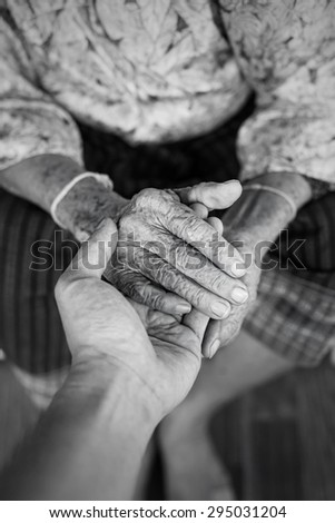 The engagement of young hand touches and holds an old wrinkled hand,monochrome.