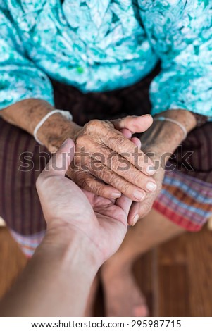 The engagement of young hand touches and holds an old wrinkled hand