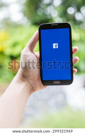 UDON THANI,THAILAND - July 24, 2015: man holding a brand samsung galaxy note 2 with Facebook logo on the screen. Facebook is a social media online service for networking communication.