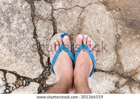 Male foot in flip-flop on street, cracked cement