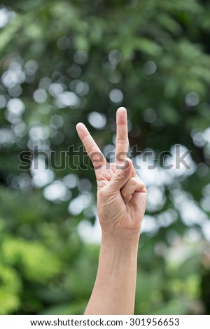 Hand with two fingers up,victory symbol on green background