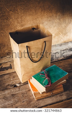 still life of old books and eyeglasses ,paper bag on wooden floor