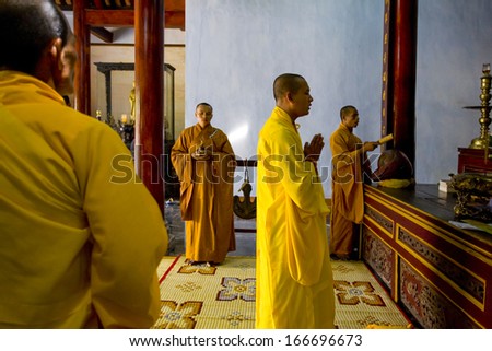 12 JUNE 2011 - HOI AN, VIETNAM - Monks in yellow and orange robes pray at the Phuoc Lam Pagoda, on 12 June 2011, in Hoi An, Vietnam