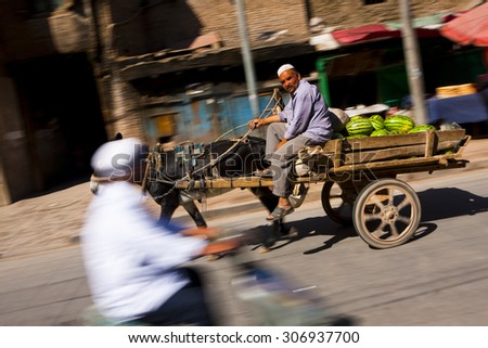 KASHGAR, CHINA - 24 AUGUST 2012 - A man drives a cart full of watermelons in Kashgar old town, Xinjiang province