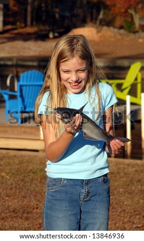 Young girl not sure about holding a catfish that she caught herself.
