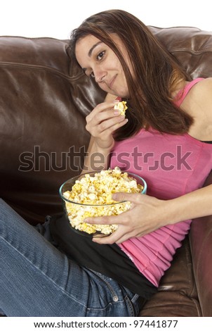 Tilted view woman sits in leather chair relaxing eating popcorn. Could be retro of housewife home watching soap opera movie night sports event on TV football baseball basketball etc. White background.