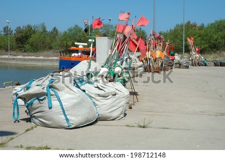 Fishing buoys and bags with fishing net on quay in small harbour