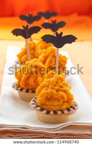 Halloween cake with orange cream decorated with a bat on a stick