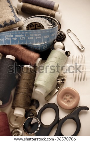 Sewing kit. Scissors, bobbins with thread and needles on the old fabric.