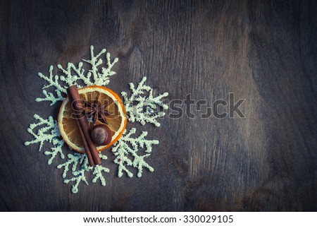Christmas decoration with dried orange, cinnamon, anise and snowflakes on a dark wooden background