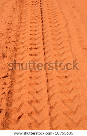 Red rural road with car tracks in dirt.