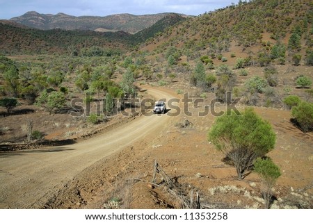 Red Australian rural road with approaching jeep.  Australia