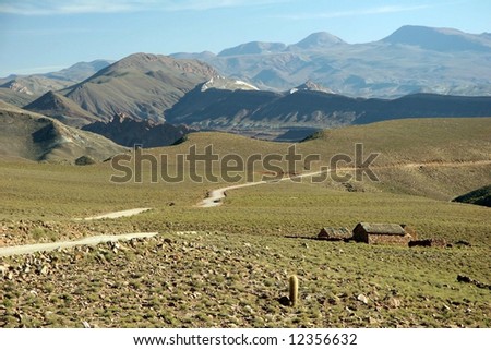 Landscape in the remote area of Bolivia. Dirt road passing the hut and mountain range. Bolivia