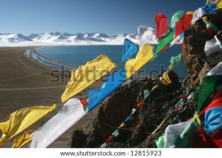 Tibetan Praying Flags with The Yamdrok Tso Lake and snowcapped mountain peaks in background. Tibet