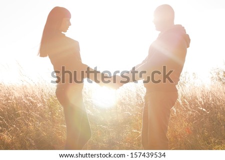 A young couple holding hands on the nature of the bright sun