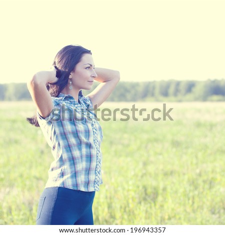 Woman in shirt looks into the distance outdoors