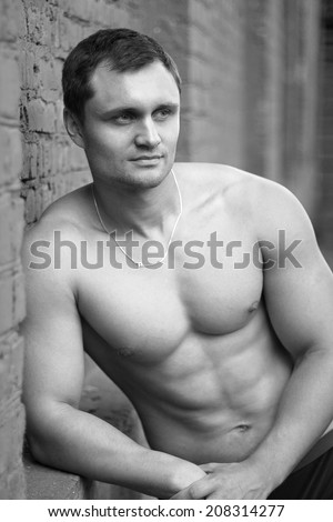 Young man athlete bodybuilder leaned against the wall