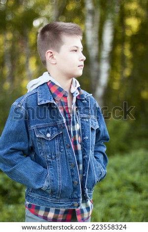 A boy stands in the park and looks into the distance