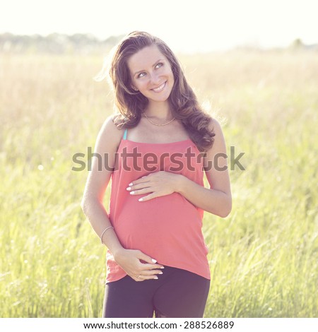 Joyful young mother dreams about the future of a child standing in the bright sunny day outdoors