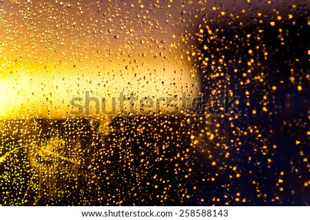 Sun dawn, drops on window glass, outline of a tower (blurred view, background)