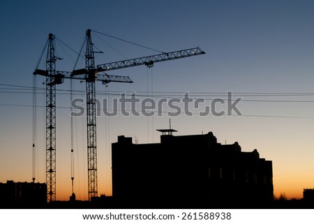 Construction - silhouettes of cranes and new buildings, evening sky
