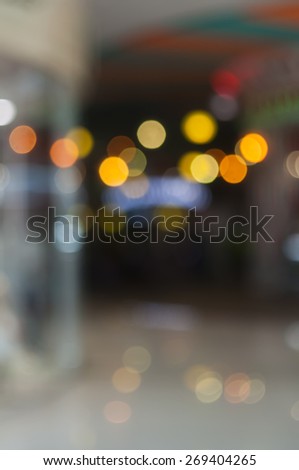 Blurred background: interior of shopping-mall gallery, shop-windows, bokeh lights, attraction, side-show, merry-go-round, roundabout