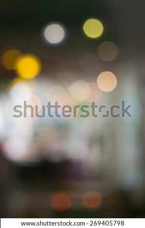Blurred background: interior of shopping-mall gallery, shop-windows, bokeh lights, attraction, side-show, merry-go-round, roundabout