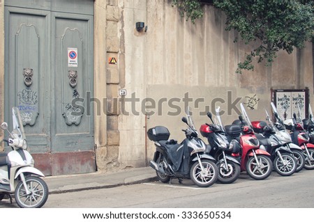 FLORENCE, ITALY, OCTOBER 27, 2015: Motorbikes parked in the italian street near old doors