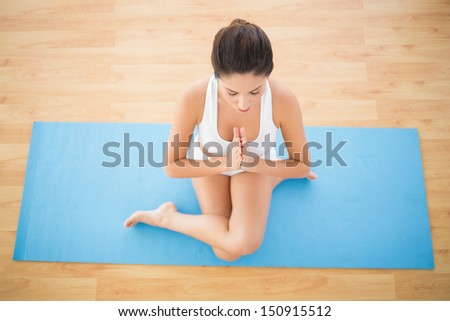 Fit woman sitting in cow face pose at home on wooden floor